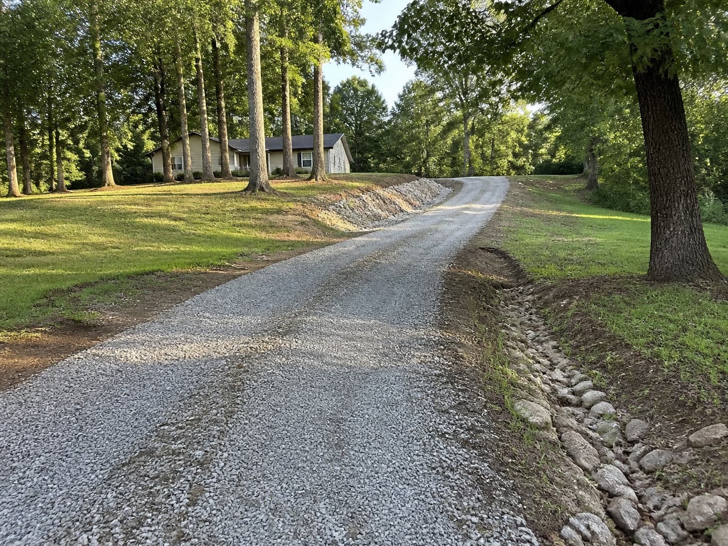 Long rural private gravel driveway with slope and drainage context